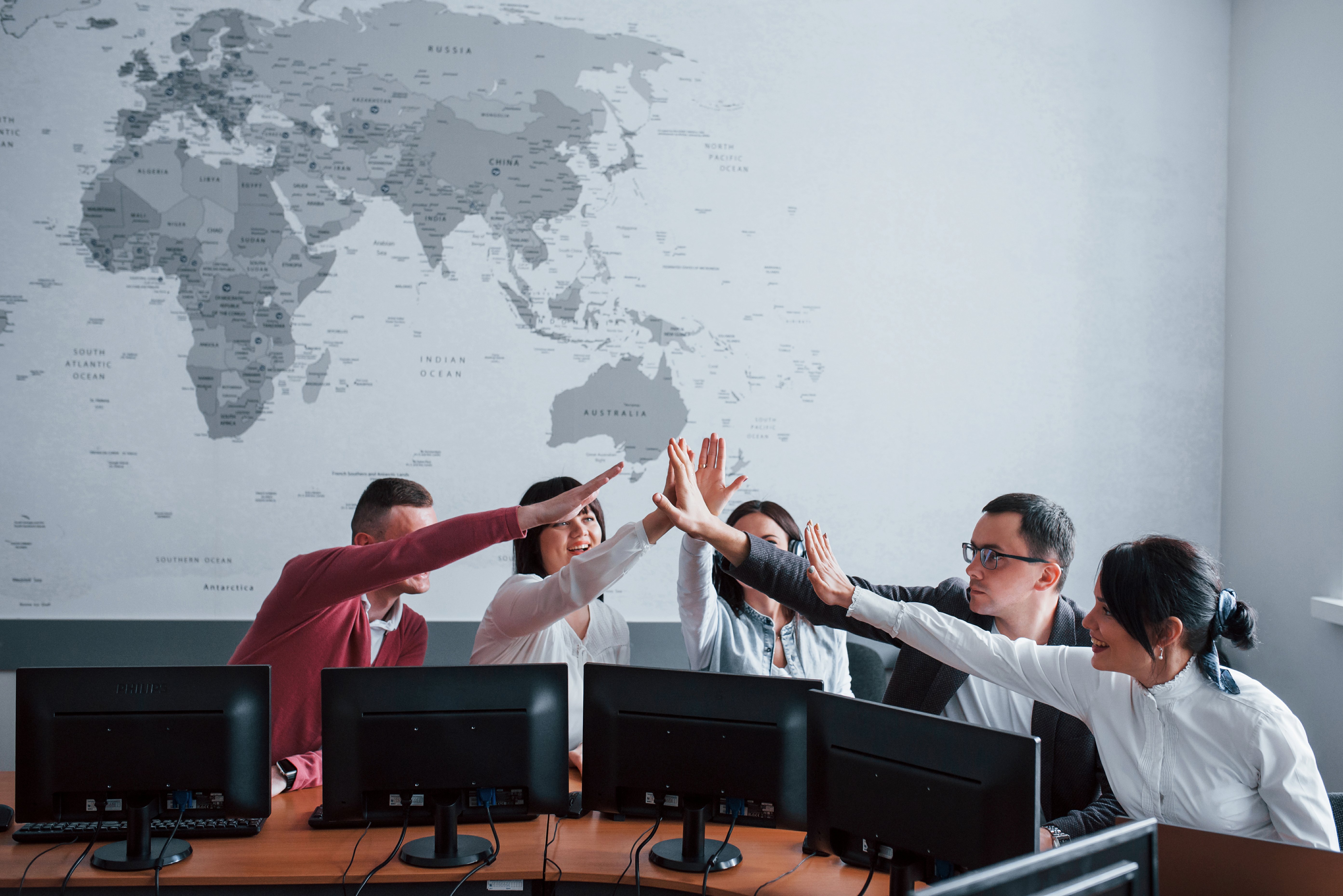 International team celebrating together in front of a world map